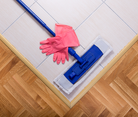 Close up of mopping stick and rubber gloves on tiled floorの写真素材