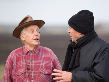 Two senior peasants talking on the field in winter timeの写真素材