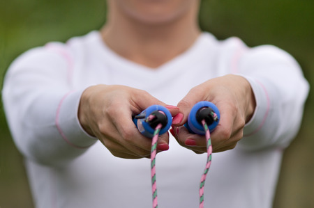 Close up of woman's hands holding skipping rope in front of her body