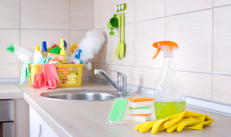Spray bottle and cleaning tools on the kitchen countertop. Basket full of cleaning supplies and equipment in backgroundの写真素材