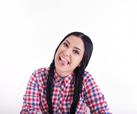 Pretty girl with two braids making silly faces with her tongue out. Isolated on white backgroundの写真素材
