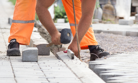 Close up of worker's hands installing and leveling road side in sidewalkの写真素材