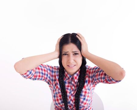 Frustrated young woman holding head with hands and looking at camera. Isolated on white backgroundの写真素材