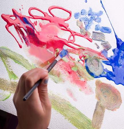 Top view of young girl holding brush and painting abstract art with watercolorsの写真素材