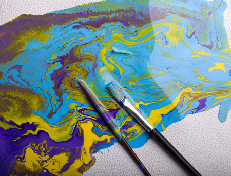 Top view of abstract colorful painting with brushes on white background