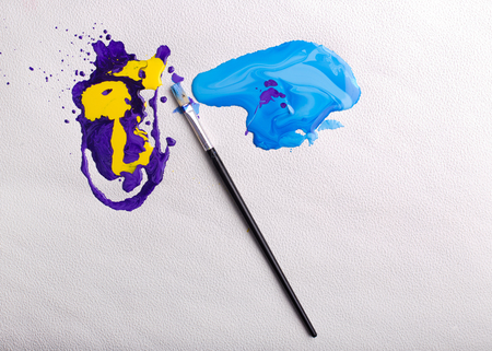 Colorful blots of dripping paints and brush on white paperの写真素材