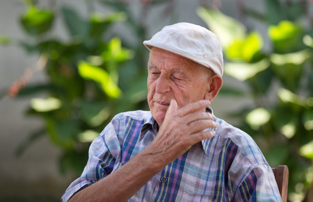 Old depressed man with disgusted face expression in courtyardの写真素材