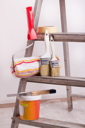 Metal ladder with painting supplies for apartment renovation on protected wooden floor with foilの写真素材