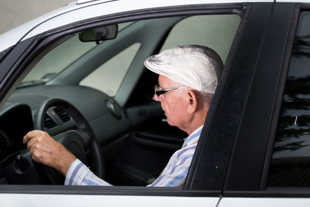 Retired elder man with glasses driving gray carの写真素材