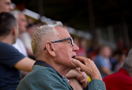 Excited old man watching sport game with open mouth. Senior people in the audienceの写真素材