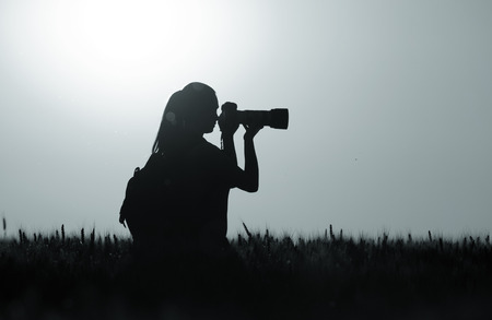 Silhouette of young girl taking nature photos in wheat field at night