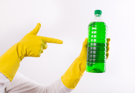 Human hand with rubber gloves pointing index finger on green liquid detergent in transparent bottle. Isolated on white backgroundの写真素材