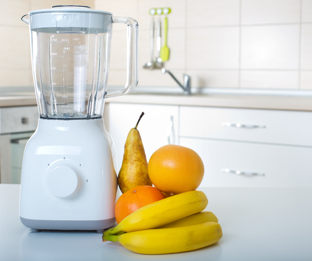 White blender standing on tabel in kitchen with fresh fruitsの写真素材