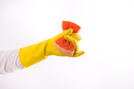 Close up of hand with rubber gloves squeezing dry sponge. Isolated on white background. Dish washing conceptの写真素材