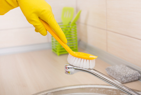 Close up of female hands with protective gloves scrubbing and cleaning kitchen faucetの写真素材