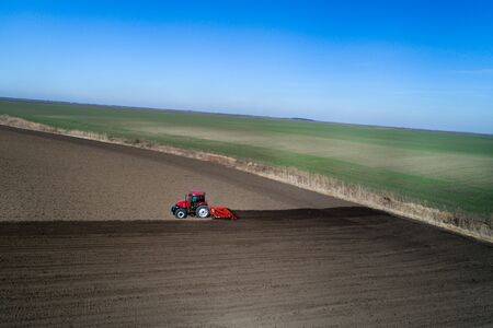 Aerial image of tractor harrowing soil in springtime shoot from drone