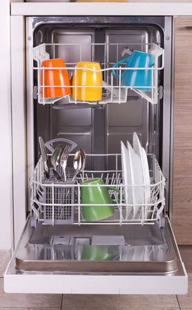 Close up of colorful dishware in open dishwasher in kitchenの写真素材