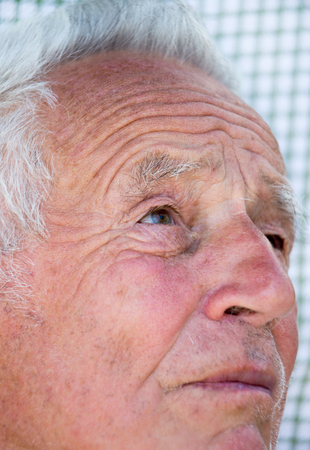 Close up of old man face with wrinkles. Senior citizen looking upの写真素材