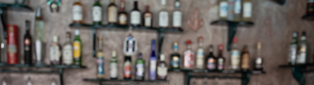 Blurred image of bar shelves with bottles of alcohol on wall as backgroundの写真素材