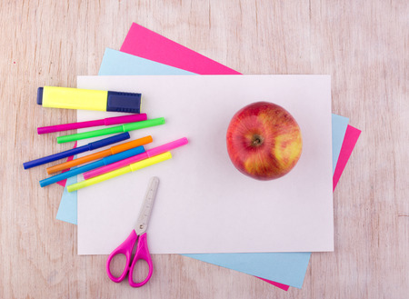 Top view of school supplies and apple on collage papers on wooden deskの写真素材