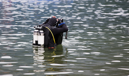 Diver with full equipment entering water in mountain lake