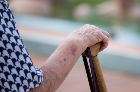 Close up of old woman's hands resting on wooden stickの写真素材