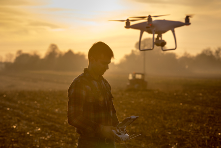 Attractive farmer navigating drone above farmland. High technology innovations for increasing...