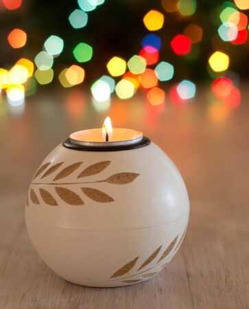 Close up of candle burning on wooden table and colorful lights in background. Christmas and New year holiday conceptの写真素材