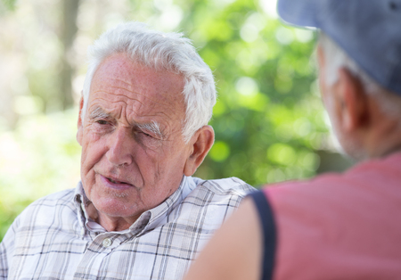 Portrait of senior man talking to his friend in parkの写真素材