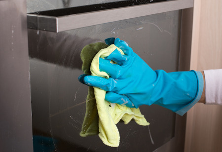 Close up of hand with protective glove wiping closed door of oven. House cleaning conceptの写真素材
