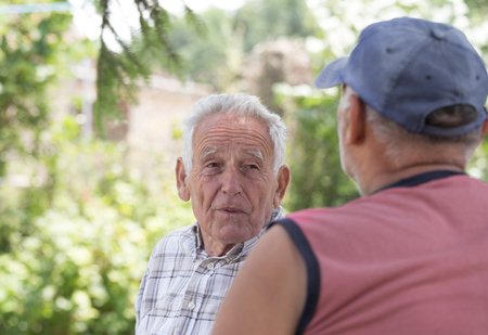 Portrait of senior man smiling and talking to his friend in parkの写真素材