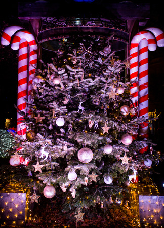 Christmas tree with ornaments and snow lighting in city at nightの写真素材