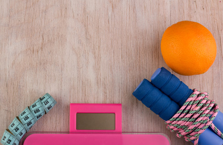 Top view of jumping rope, scale, measuring tape and orange fruit on wooden background. Fitness and dieting conceptの写真素材