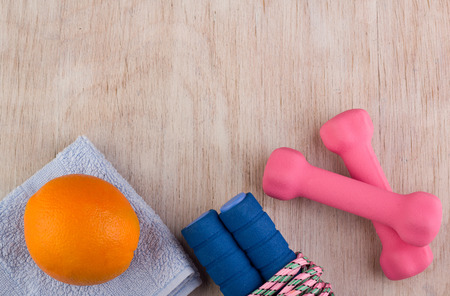 Top view of jumping rope, dumbbells and orange fruit on wooden background. Fitness and healthy lifestyle conceptの写真素材