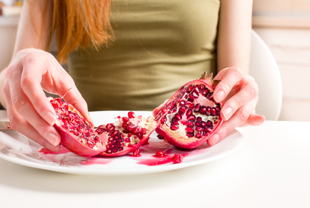 Close up of pomegranate in plate with skinny girl in backgroundの写真素材