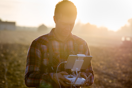 Farmer holding remote control with tablet for drone in field. High technology innovations for...