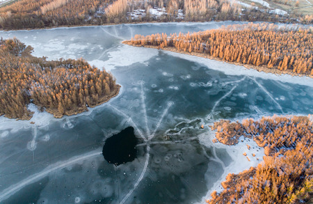 Top view of frozen river with snow on reeds, trees and ground. Aerial image shoot from droneの写真素材