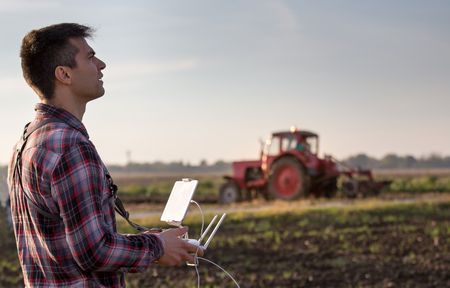 Attractive farmer navigating drone above farmland. High technology innovations for increasing productivity in agricultureの写真素材