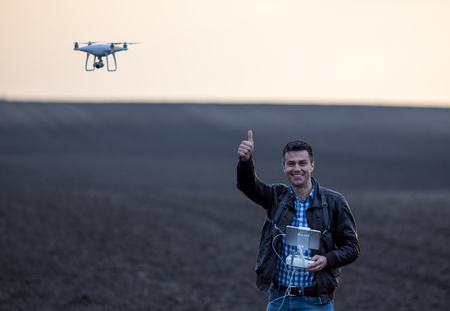 Satisfied farmer navigating drone in field. High technology innovations for increasing productivity...