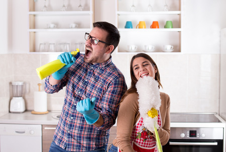 Happy young couple doing chores, singing and having funの写真素材