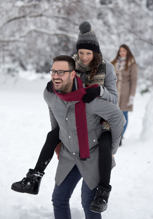 Happy smiling couple enjoying on snow in forest. Man lifting girl in front of white treesの写真素材