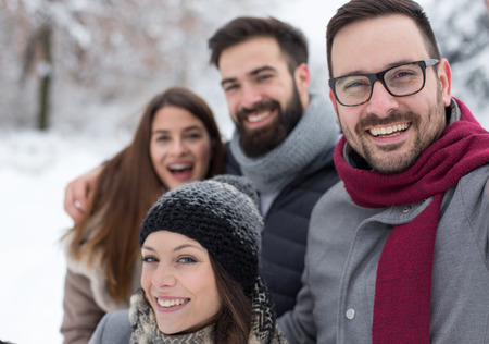 Group of friends taking selfie in snowy forest, enjoying winter holidays