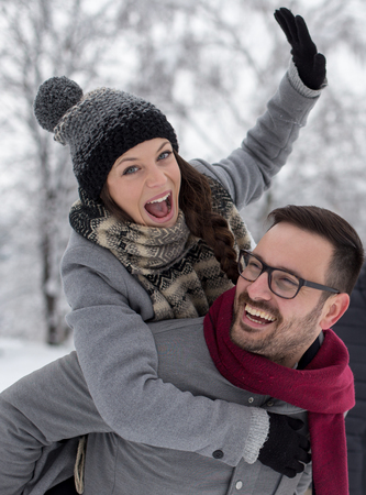 Portrait of happy young couple hugging on snow in forest