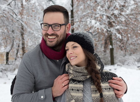 Portrait of happy young couple hugging on snow in forestの写真素材