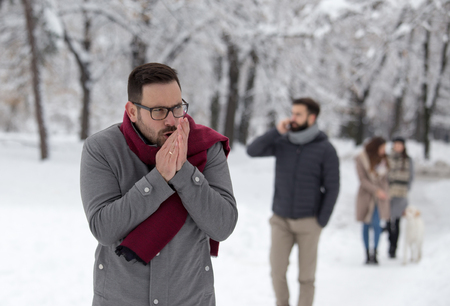 Man freezing on snow, blowing hands in forestの写真素材