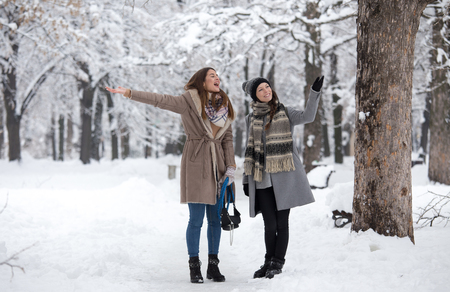 Two happy adult girls enjoying winter on snow in parkの写真素材