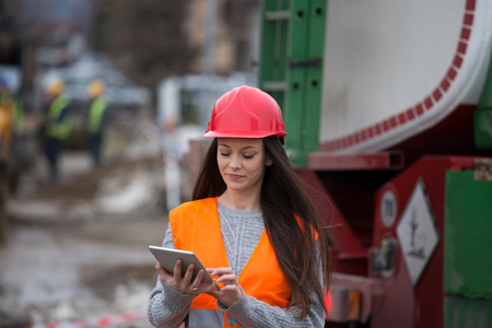 Pretty young woman engineer with tablet standing at construction site