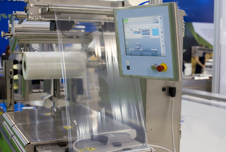 Close up of food packaging machine display in front of stretched foil