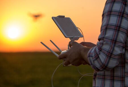 Close up of farmer's hands holding remote control of drone in field