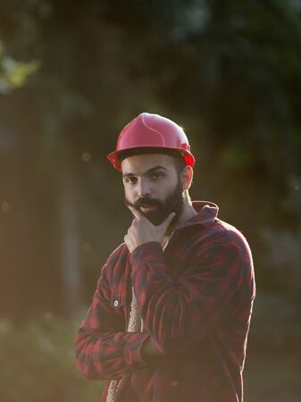 Portrait of young lumberjack with beard and helmetの写真素材